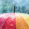 Bunter Regenschirm mit roten, orangefarbenen, gelben und grünen Segmenten im starken Regen, symbolisiert Wetterschutz und Langlebigkeit