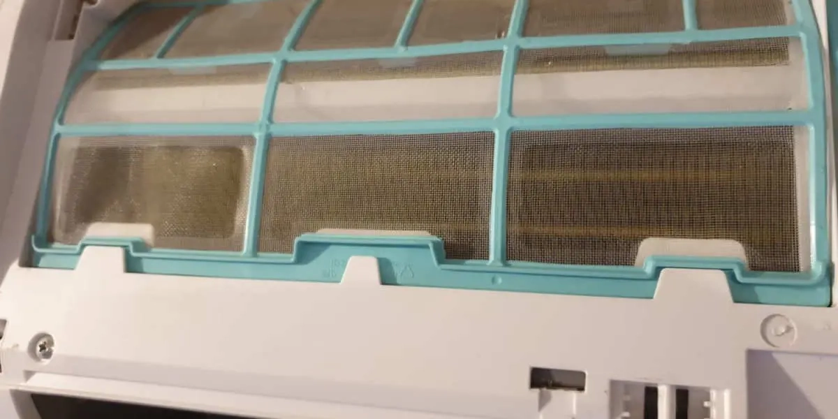 Close-up of a dirty air conditioner filter covered in dust, highlighting the need for regular HVAC maintenance and cleaning