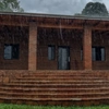 Lluvia intensa sobre un techo de tejas en Paraguay con una canaleta desbordada y fachada mojada